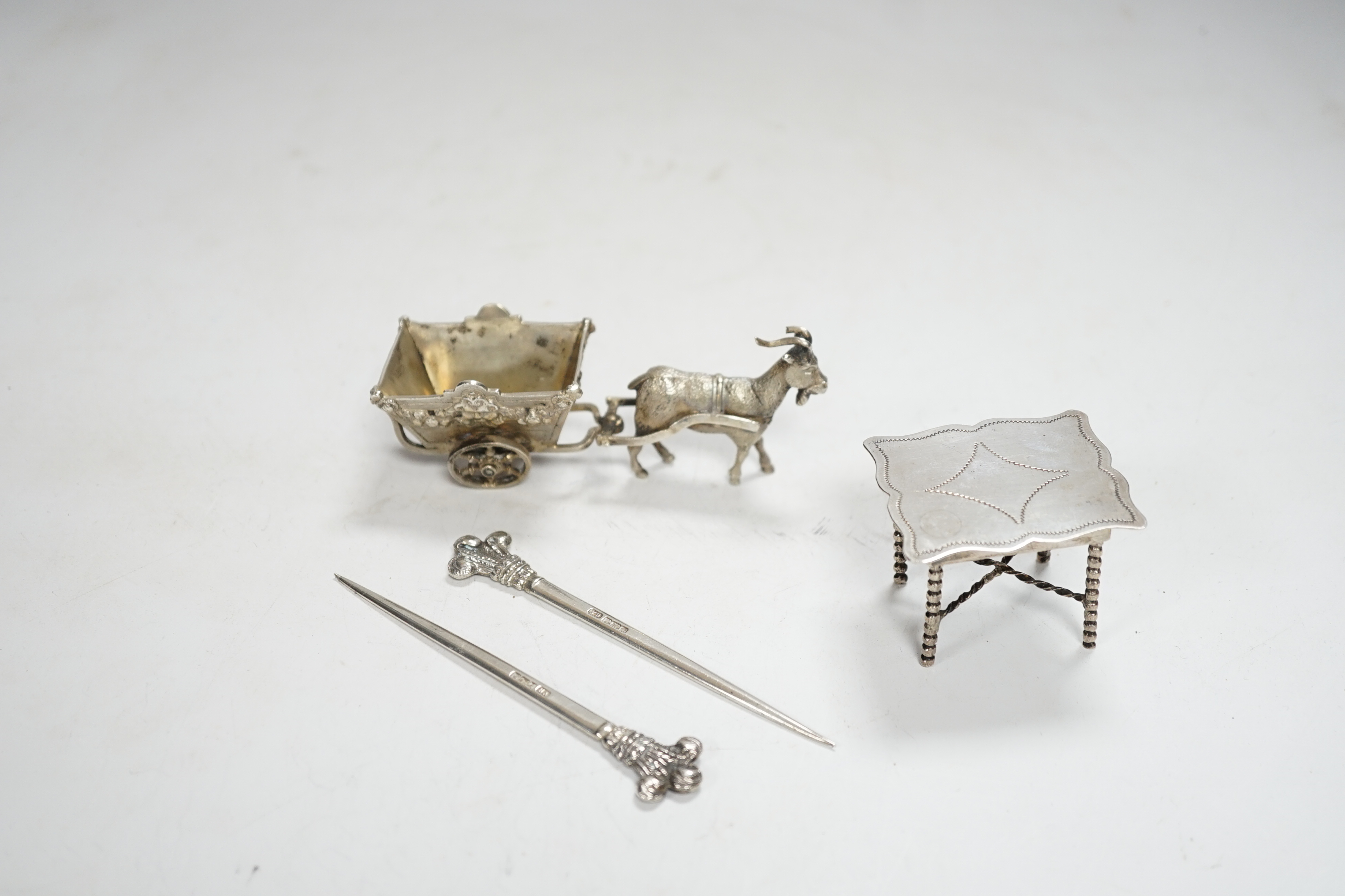 A pair of George V silver game skewers, with Prince of Wales feathers terminals, Atkin Brothers, Sheffield, 1915, 10.1cm, a Hanau? white metal miniature model of a goat pulling a cart and a Dutch white metal miniature mo